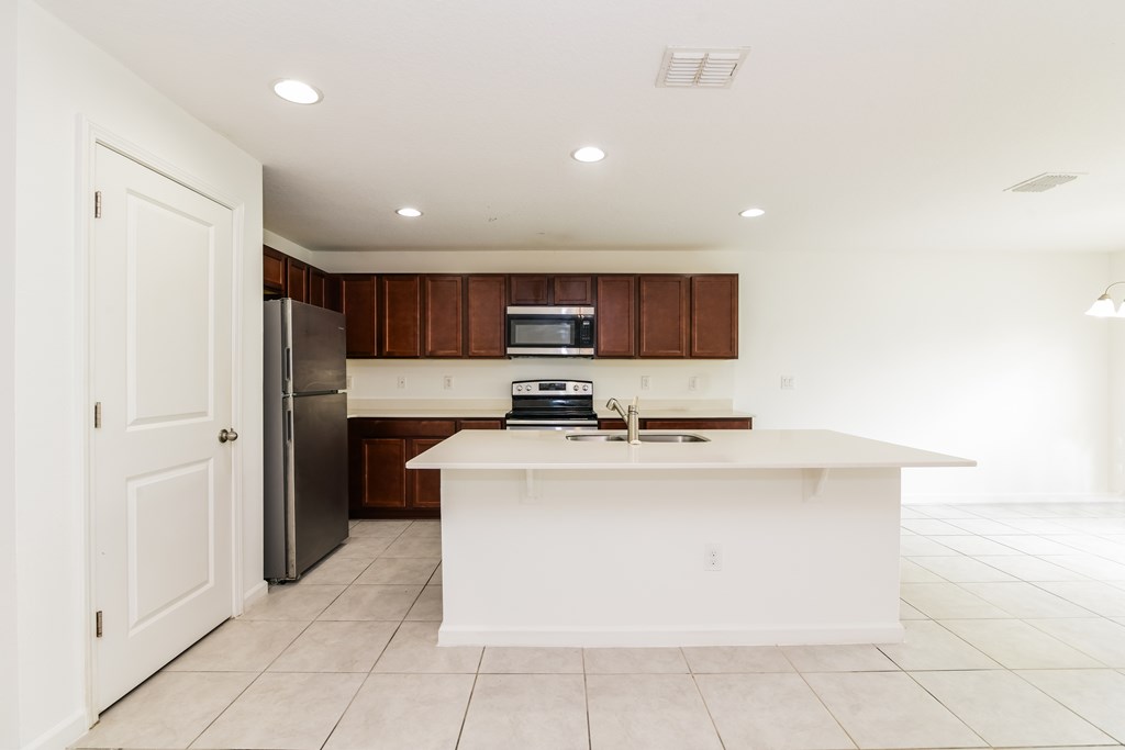 A kitchen with white countertops and brown cabinets.