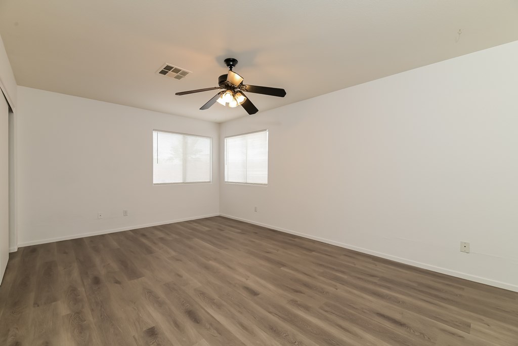 A room with a ceiling fan and wooden flooring.