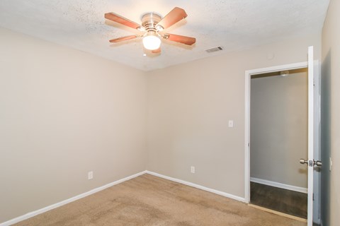 A room with a ceiling fan and a door.