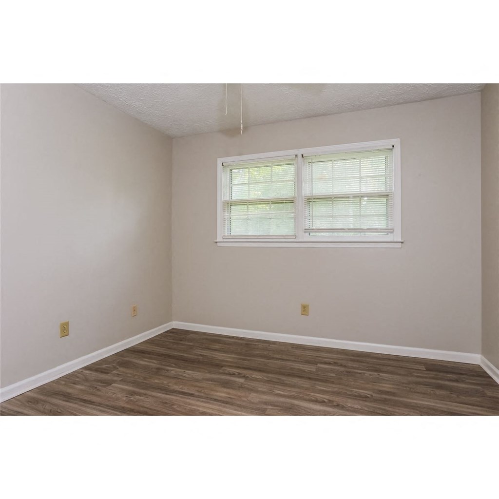 a bedroom with a window and a wooden floor