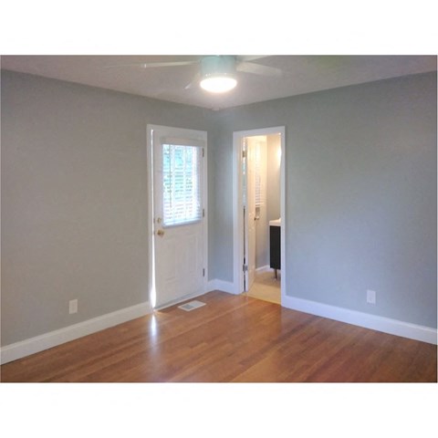 an empty living room with wood floors and a white door