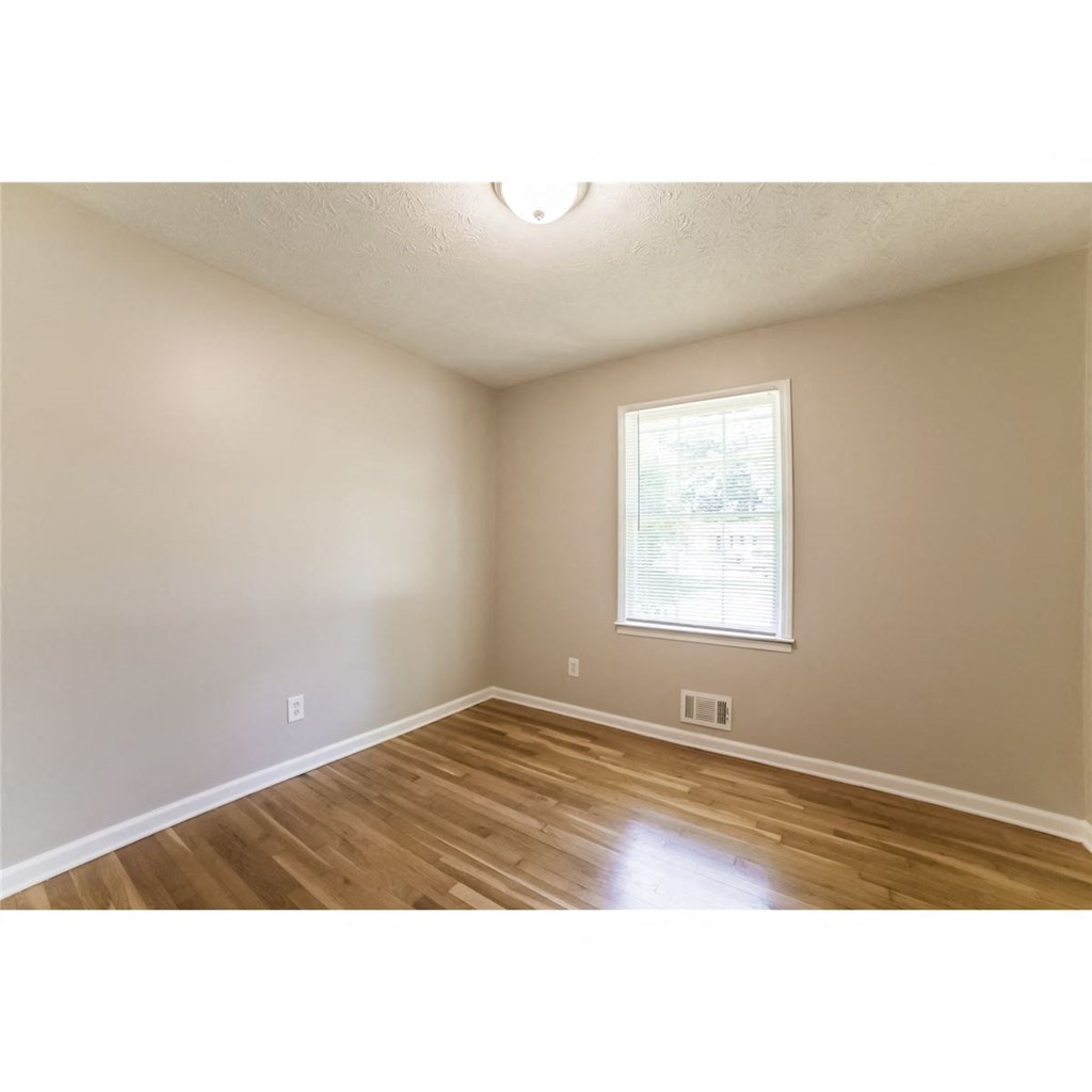 an empty room with wood floors and a window