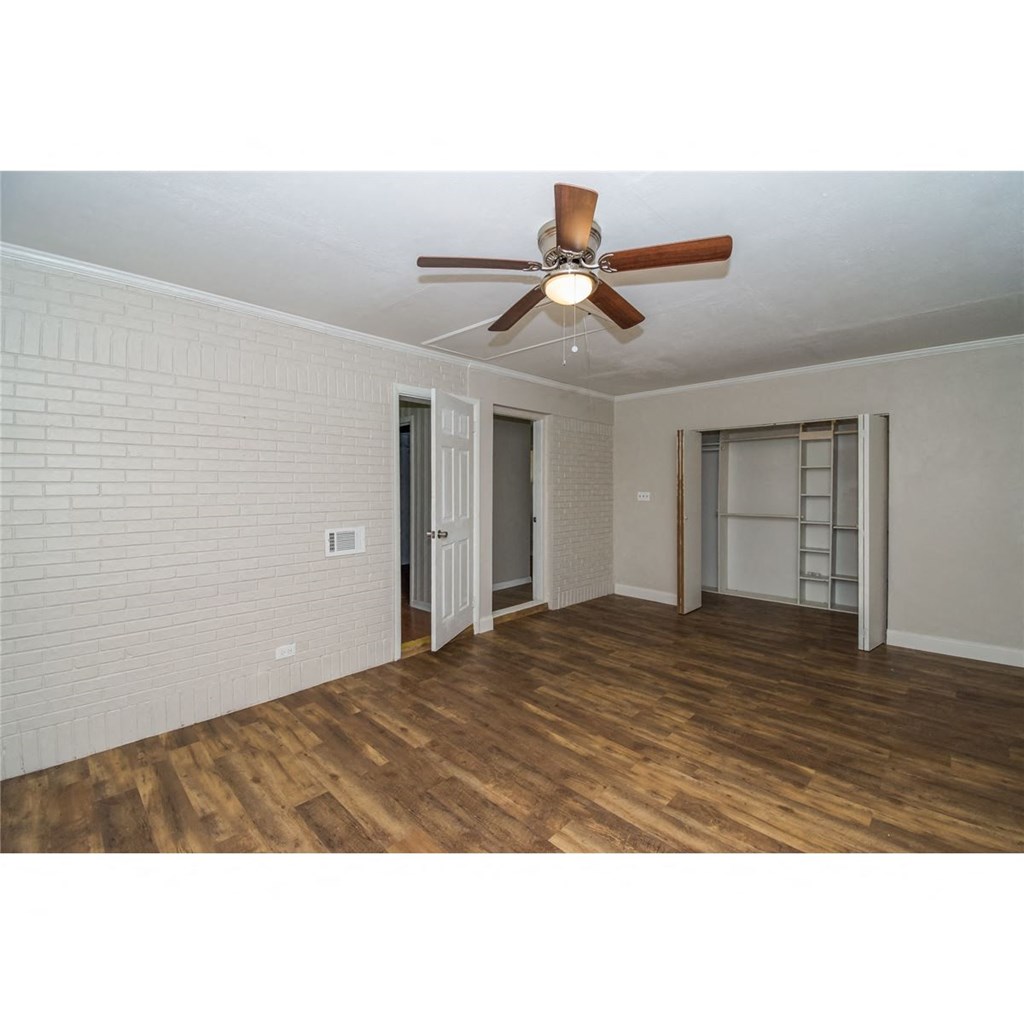 an empty living room with a ceiling fan and a closet