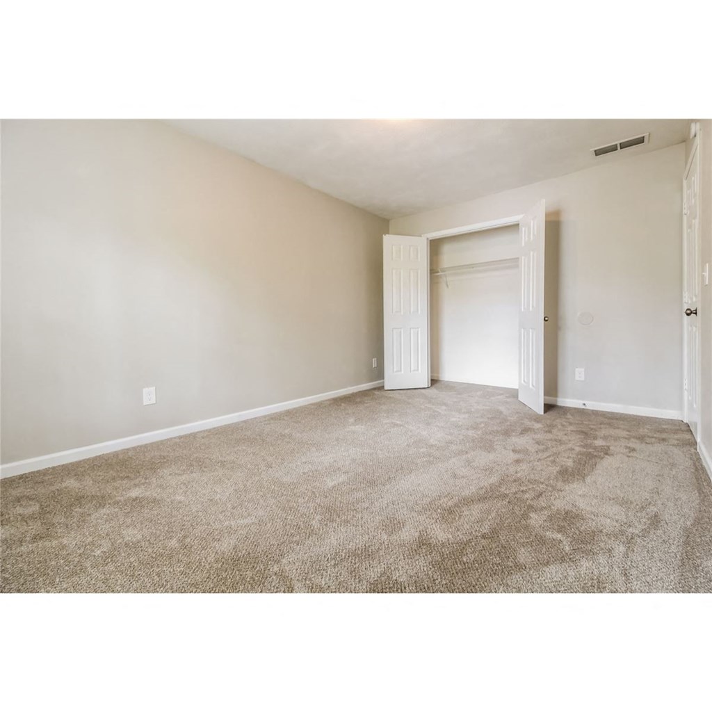 an empty living room with carpet and a door to a closet