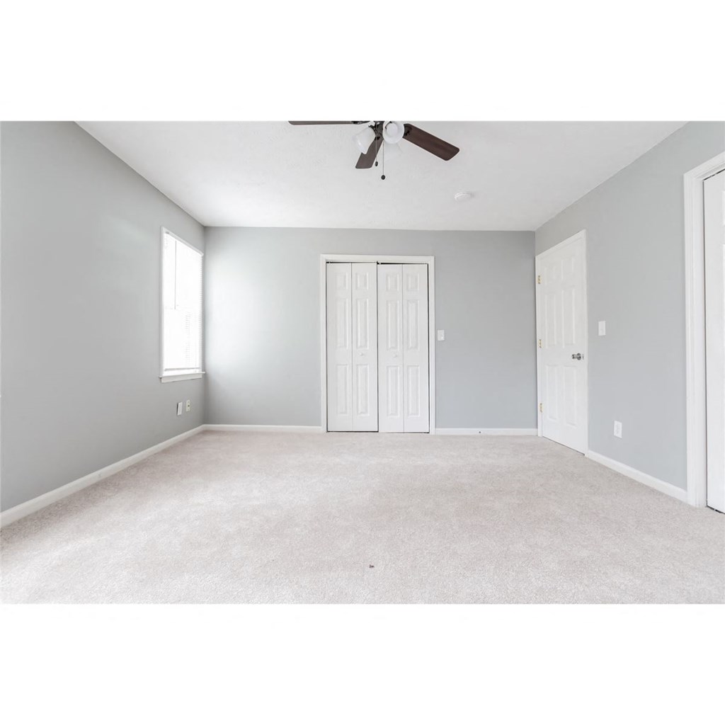 an empty living room with a ceiling fan and a door