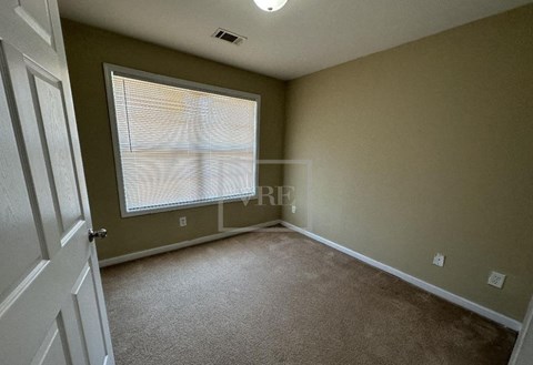 A room with a carpeted floor and a window with blinds.