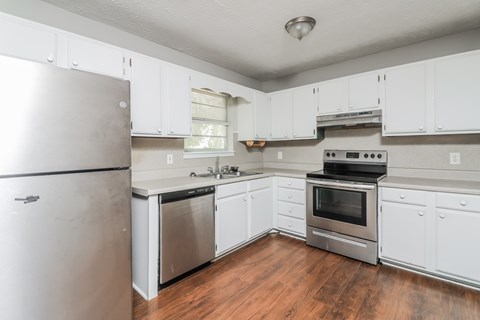 A kitchen with white cabinets and a stainless steel refrigerator.