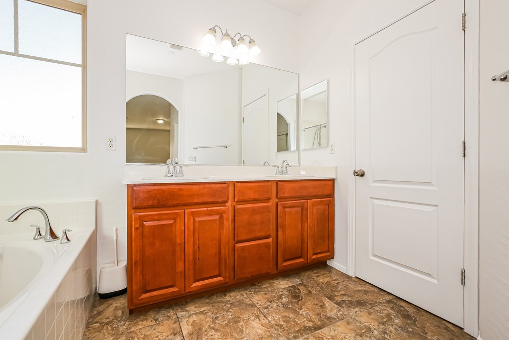 A bathroom with a white tub and a wooden vanity.