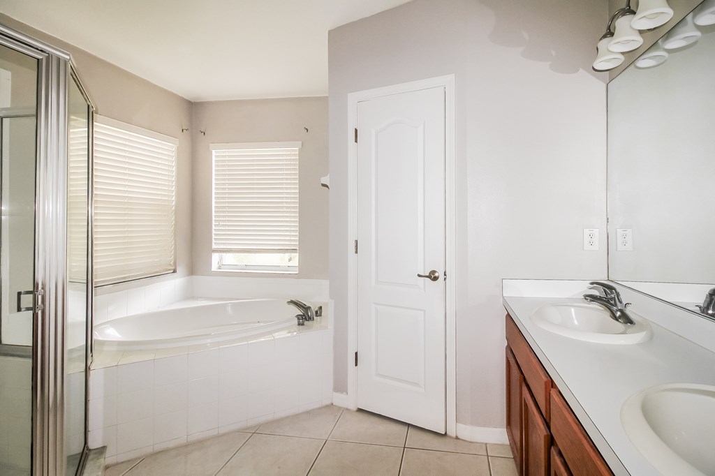 A white bathroom with a tub, sink, and mirror.