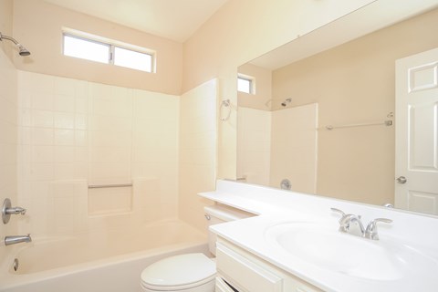 A white bathroom with a toilet, sink, and bathtub.