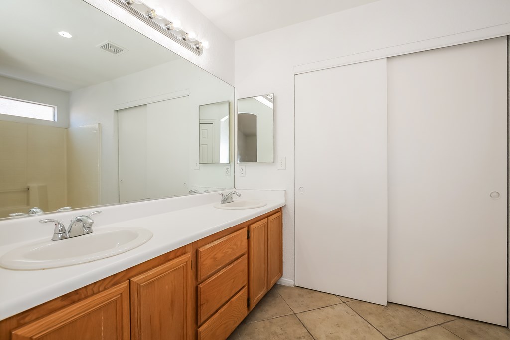 A bathroom with a white sink and wooden drawers.