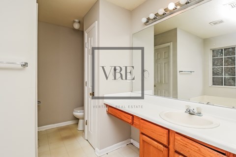 A bathroom with a white sink and a mirror with a picture frame on it.