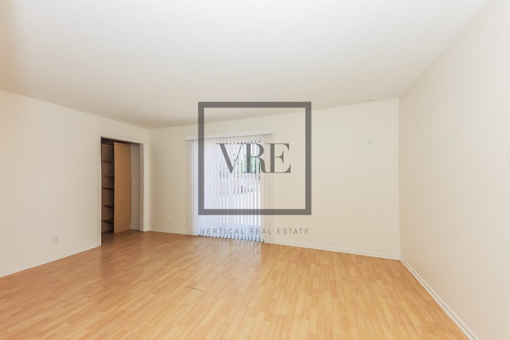 A large empty room with a wooden floor and a framed picture on the wall.