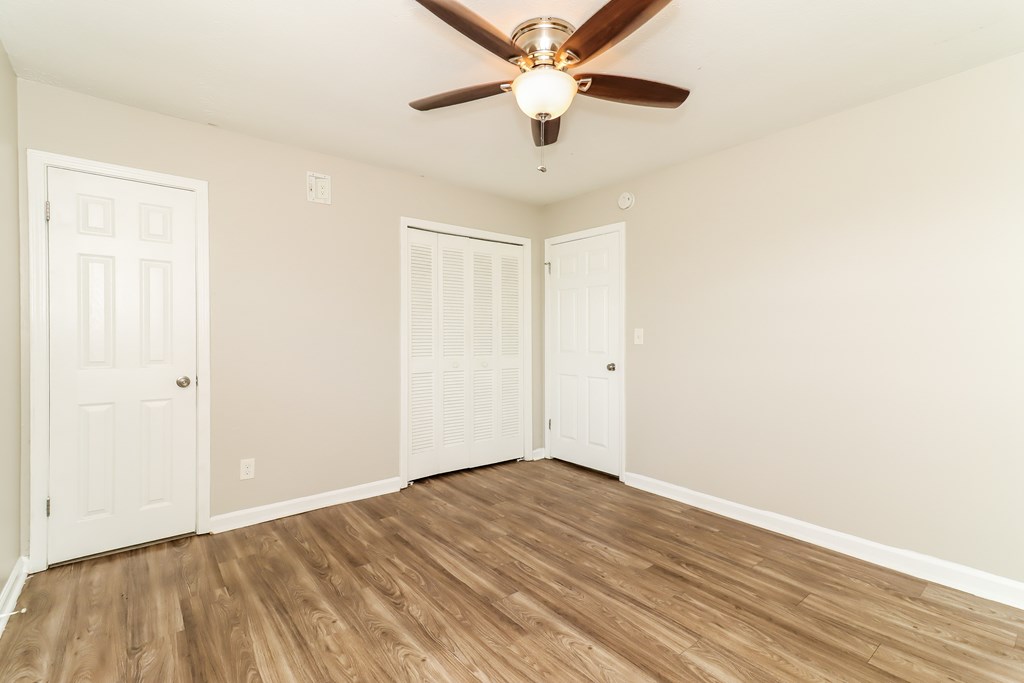 A room with a ceiling fan and wooden flooring.
