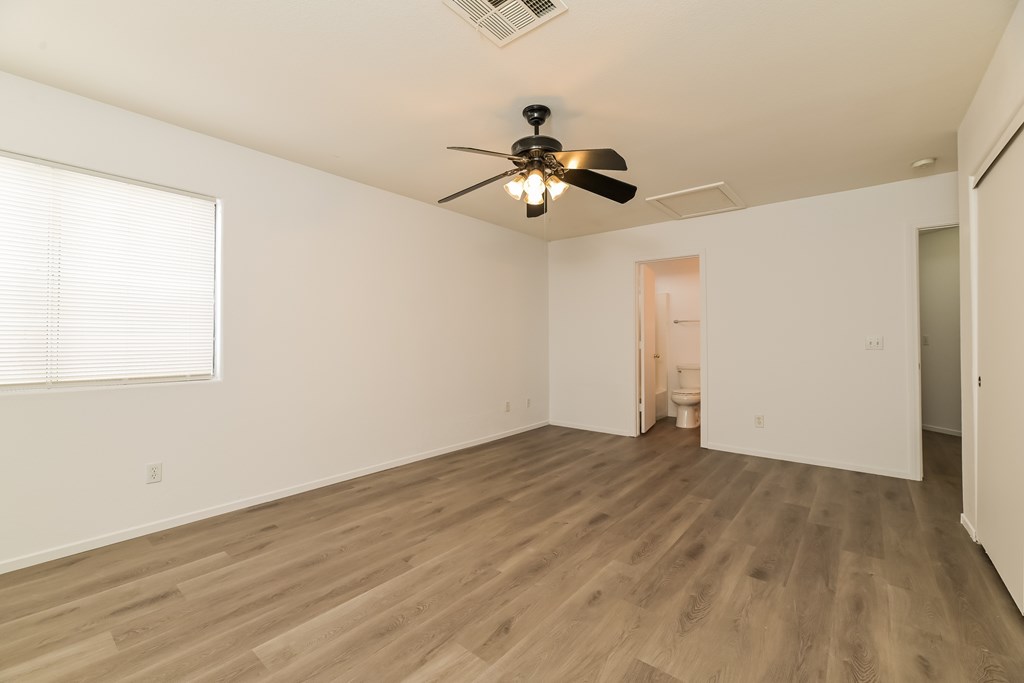A room with a ceiling fan and wooden flooring.