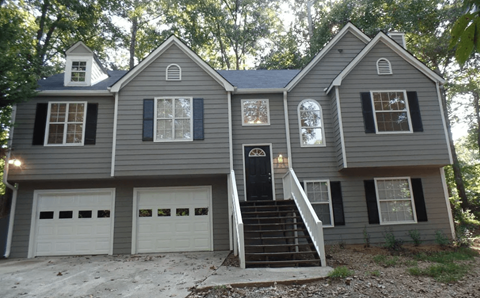 A two-story house with a black front door and white garage doors.