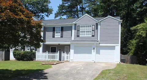 A two-story house with a grey exterior and white garage doors.