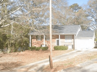 A house with a white garage door is in front of a tree.