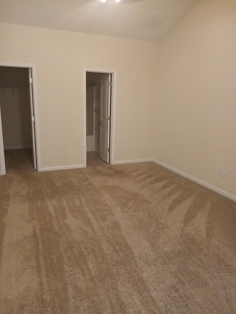 an empty living room with carpet and a door to a hallway