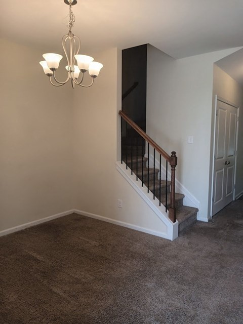 a room with a carpeted staircase and a chandelier