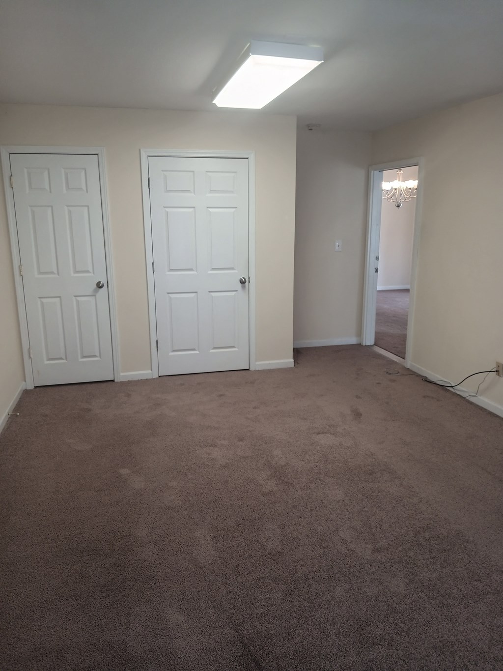 an empty living room with two doors and a carpeted floor