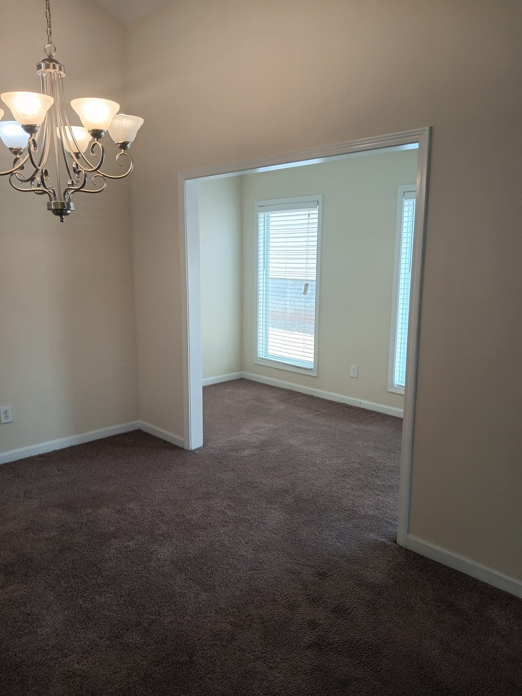 an empty living room with a chandelier and a window