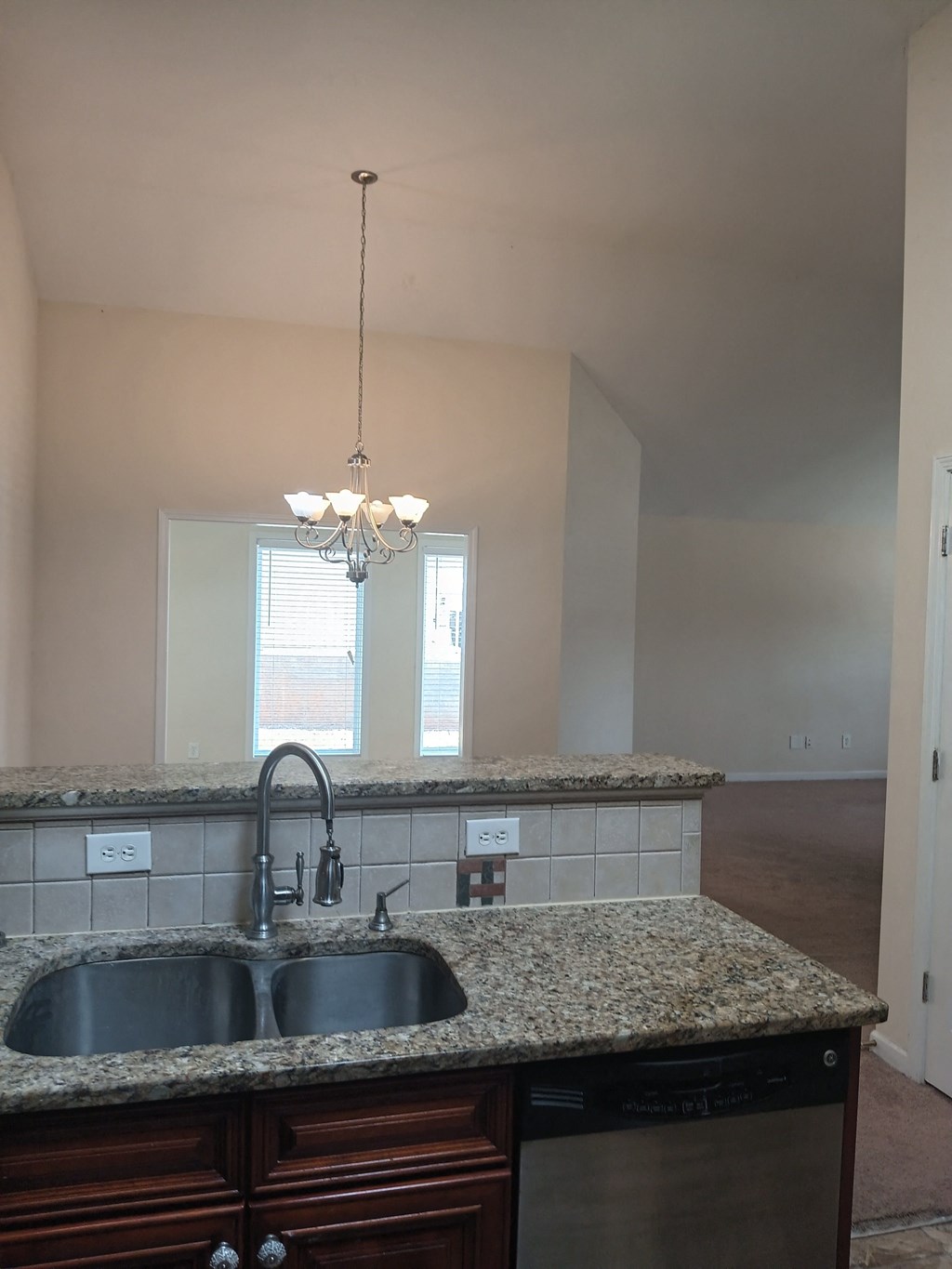 an empty kitchen with granite counter tops and a sink