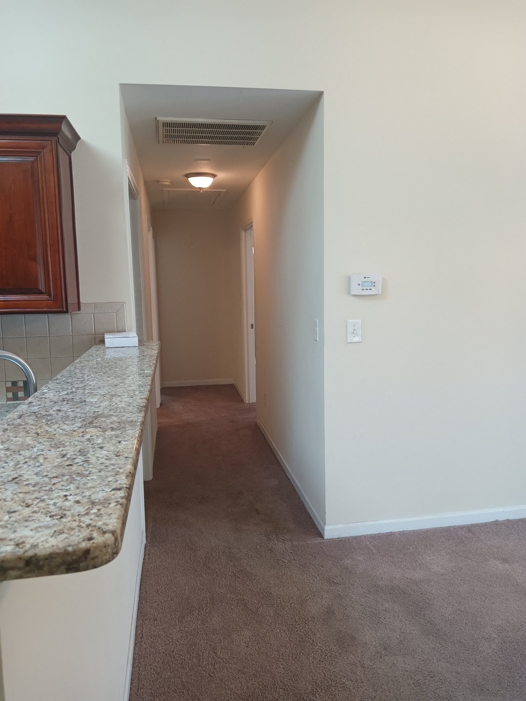a view of the hallway from the kitchen of an empty apartment