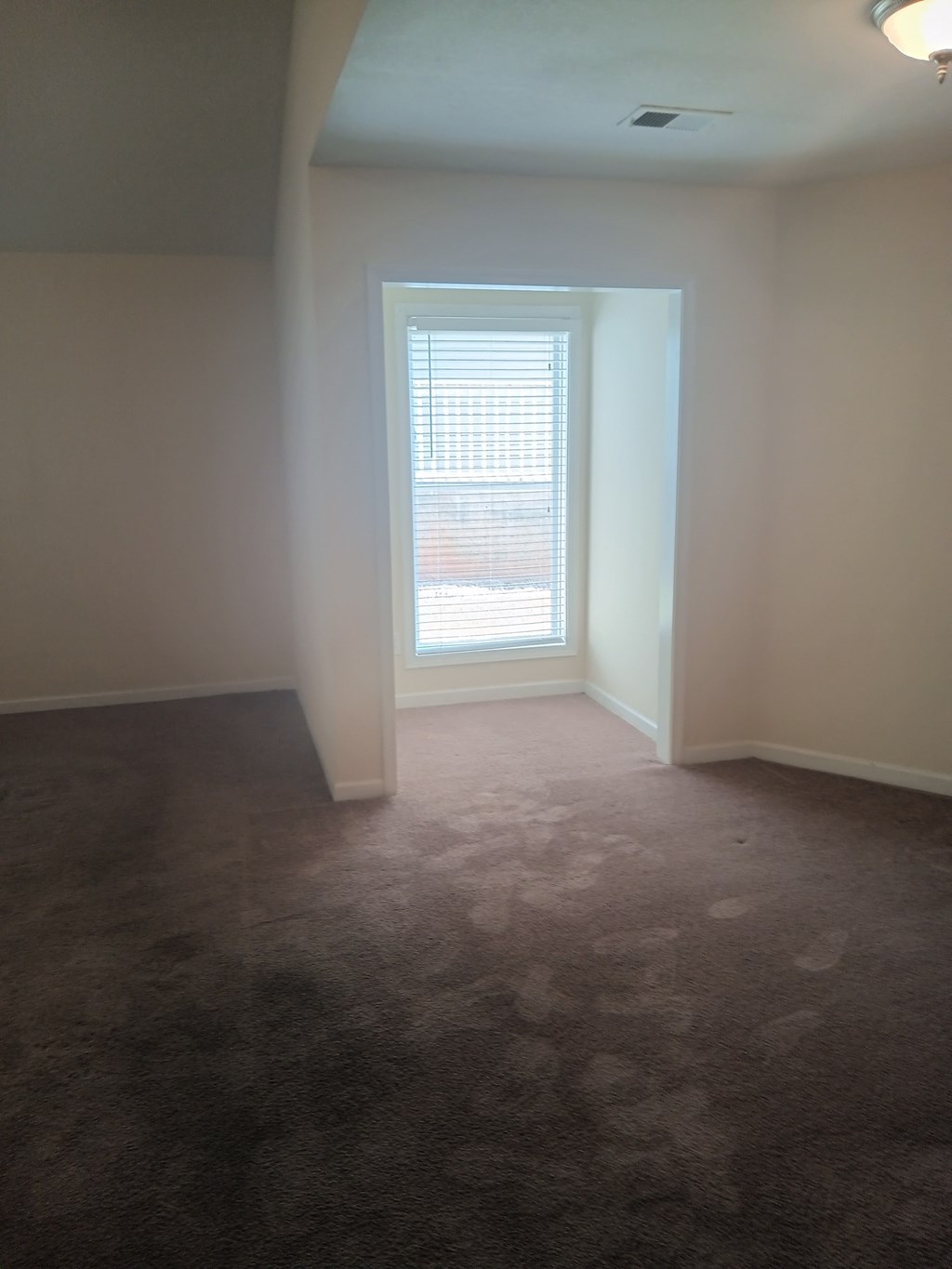 an empty living room with a window and carpet