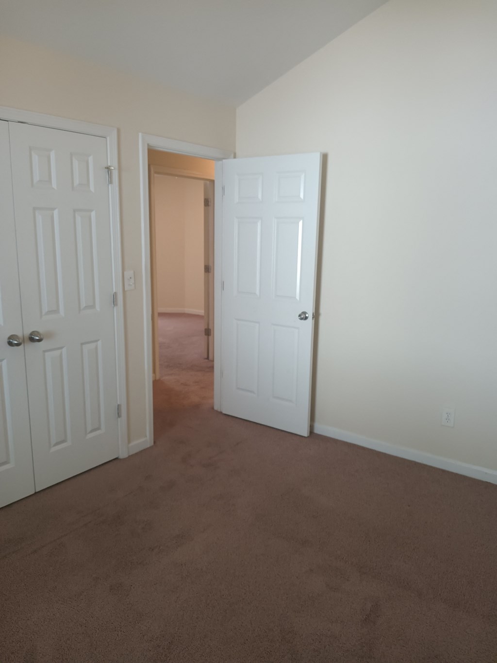 an empty room with two doors and a hallway with a door open