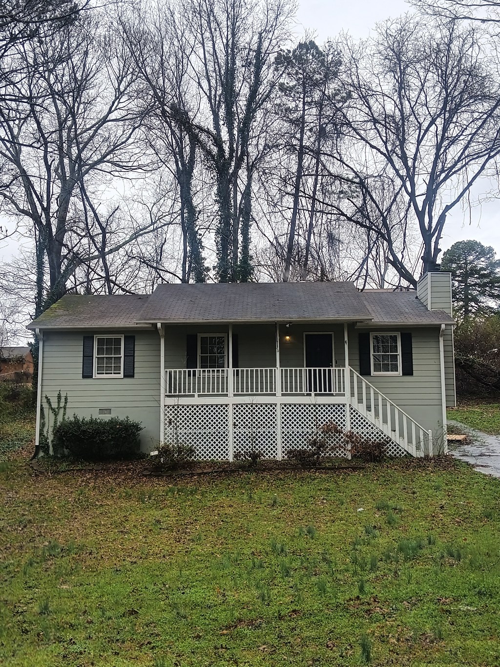 A small house with a porch and a white fence.