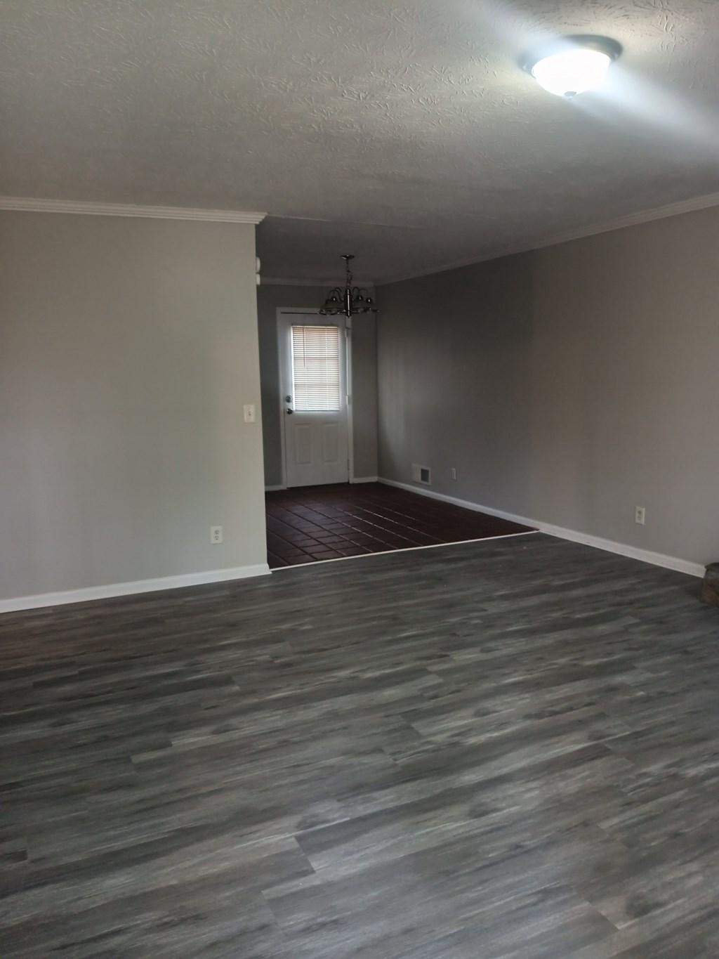 A room with a grey floor and a door on the left side.