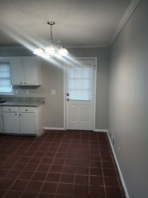 A kitchen with white cabinets and a brown tile floor.