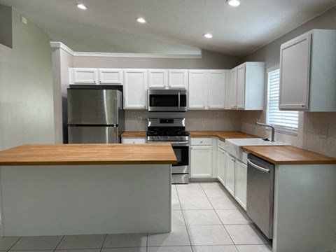 A kitchen with white cabinets and a wooden island.