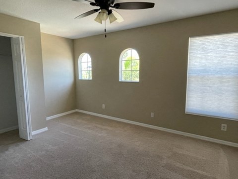 an empty living room with a ceiling fan and a window