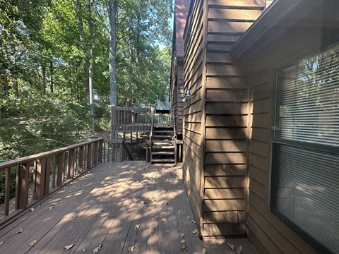 A wooden deck with a staircase leading to a deck in the back.