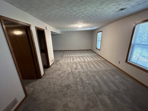 A room with a carpeted floor and a window with blinds.