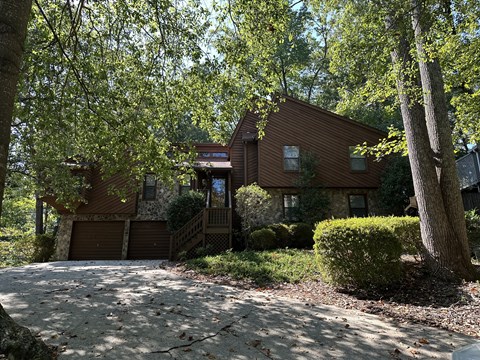 A house with a brown roof and a driveway in front of it.
