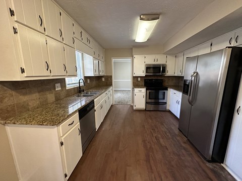 A kitchen with white cabinets and a granite countertop.