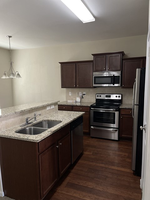 A kitchen with brown cabinets and a stainless steel oven.