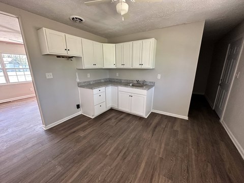 A kitchen with white cabinets and a wooden floor.