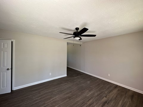 A room with a ceiling fan and wood flooring.