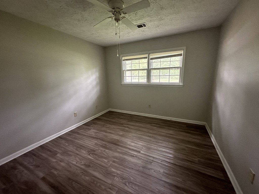 a empty room with wooden floors and a ceiling fan