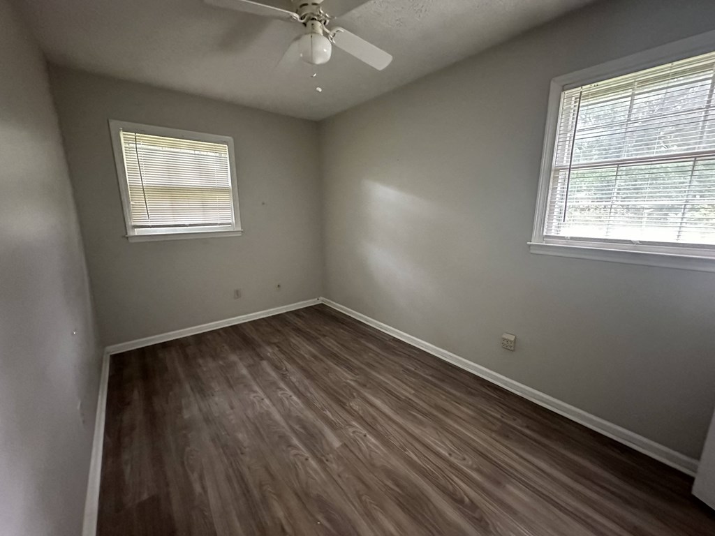 an empty bedroom with wooden floors and a ceiling fan
