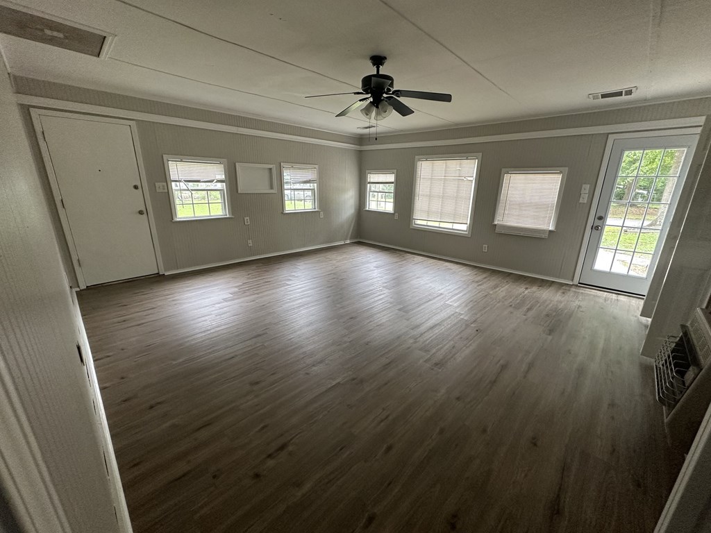 an empty living room with wood floors and a ceiling fan