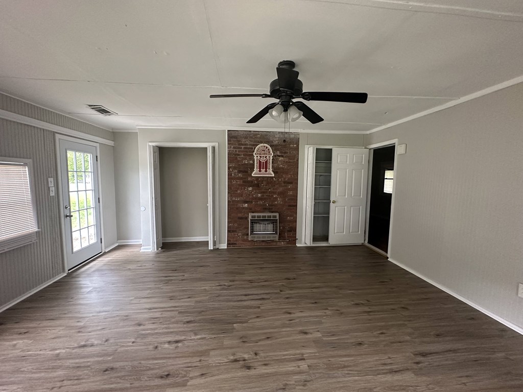 an empty living room with a ceiling fan and a brick fireplace