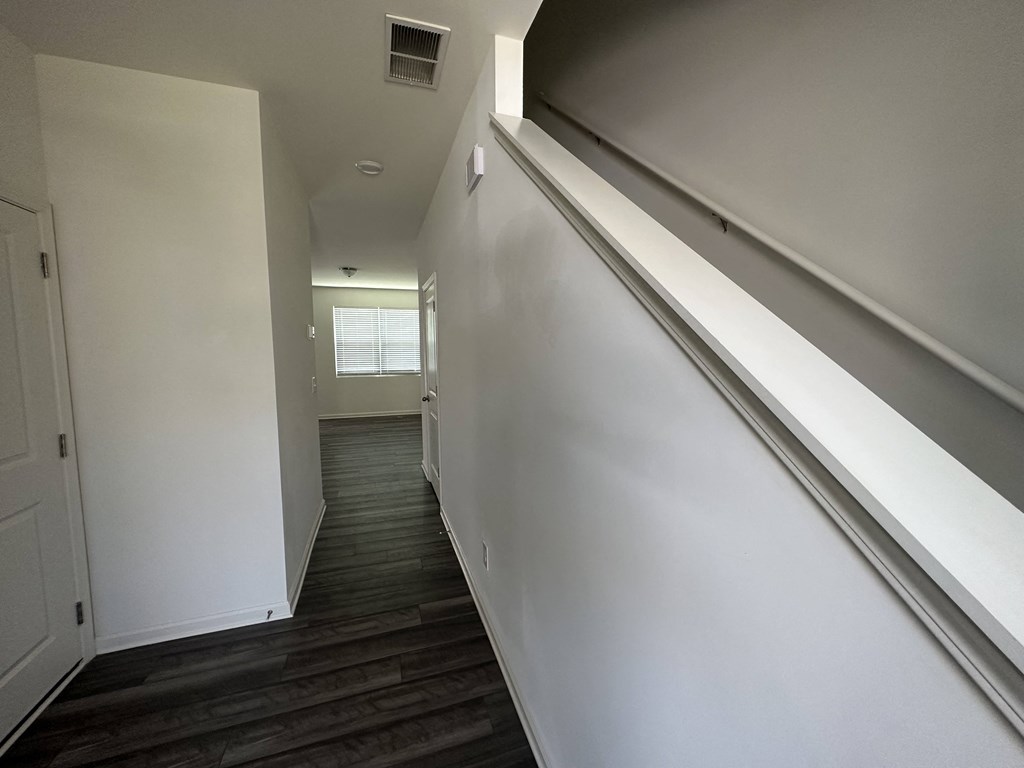 a look down the hallway of a house with white walls and stairs