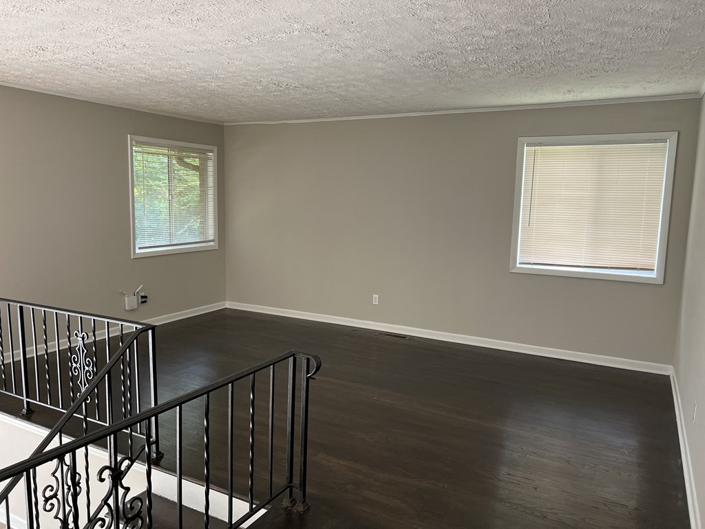 an empty living room with a staircase and wood floors