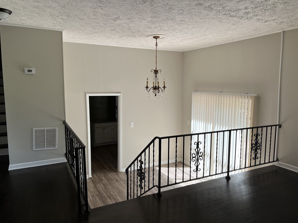 the view from the top of the stairs looking down into the living room and kitchen