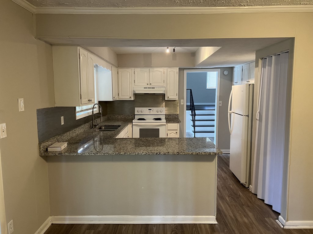 a kitchen with granite counter tops and white cabinets